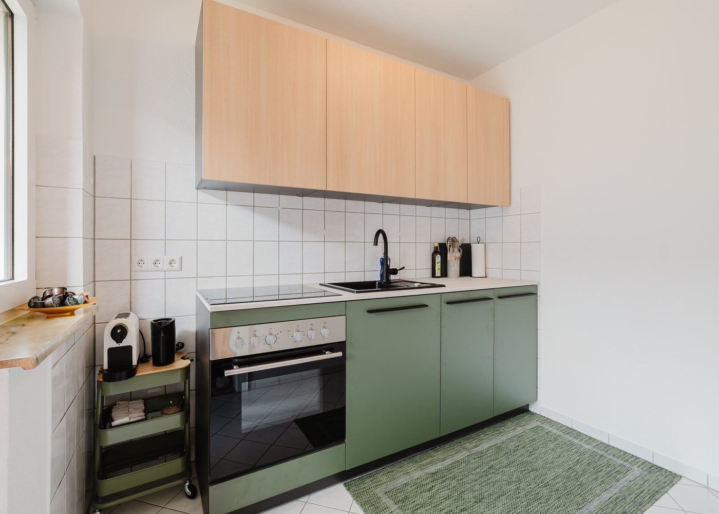 Küche des Beetle Apartments in Wolfsburg mit olivgrünen Fronten, Backofen und Induktionskochfeld