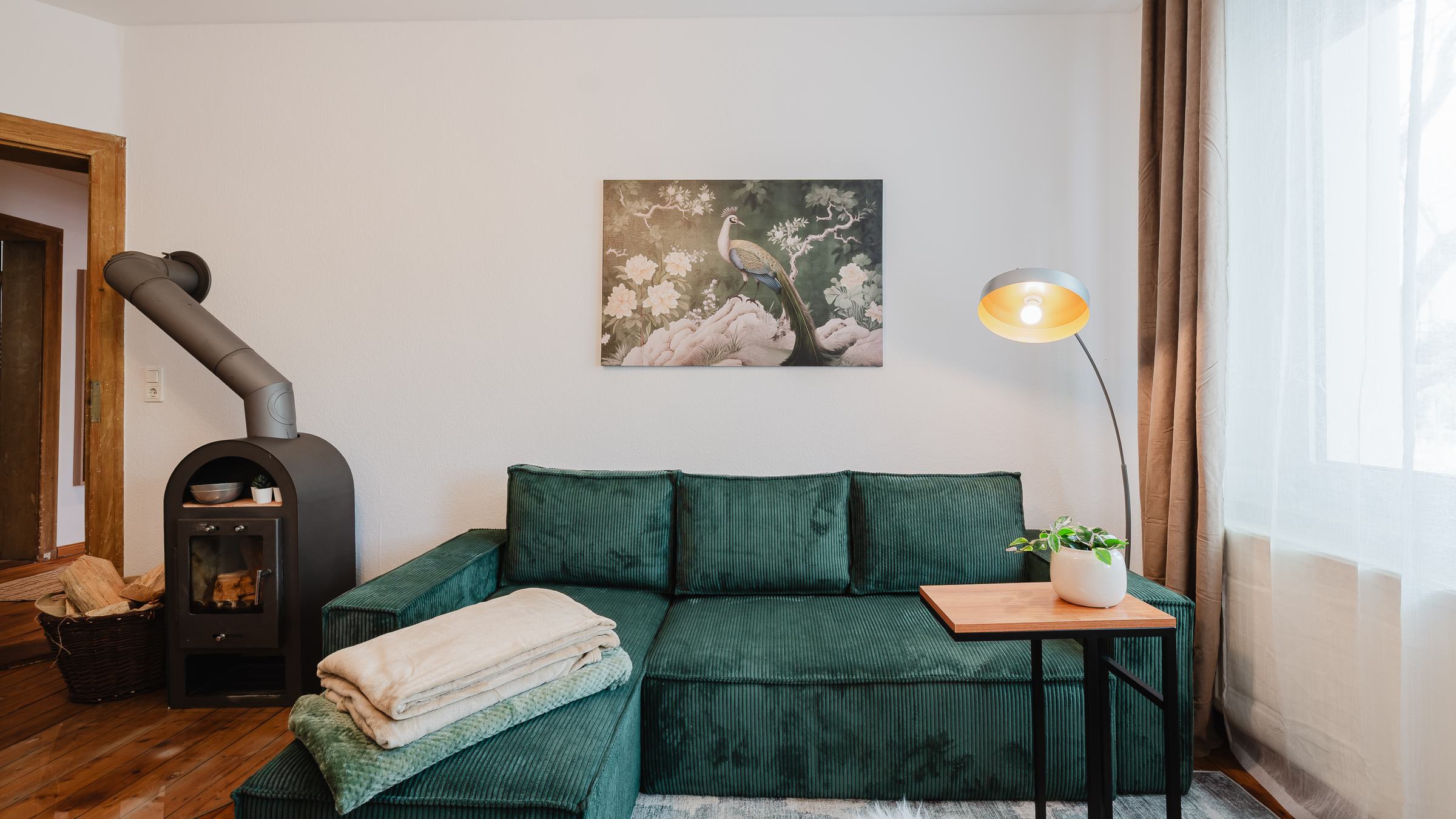 Wohnzimmer im Altbautraum mit gusseisernem Kaminofen, grüner Samtcouch und Dielenboden