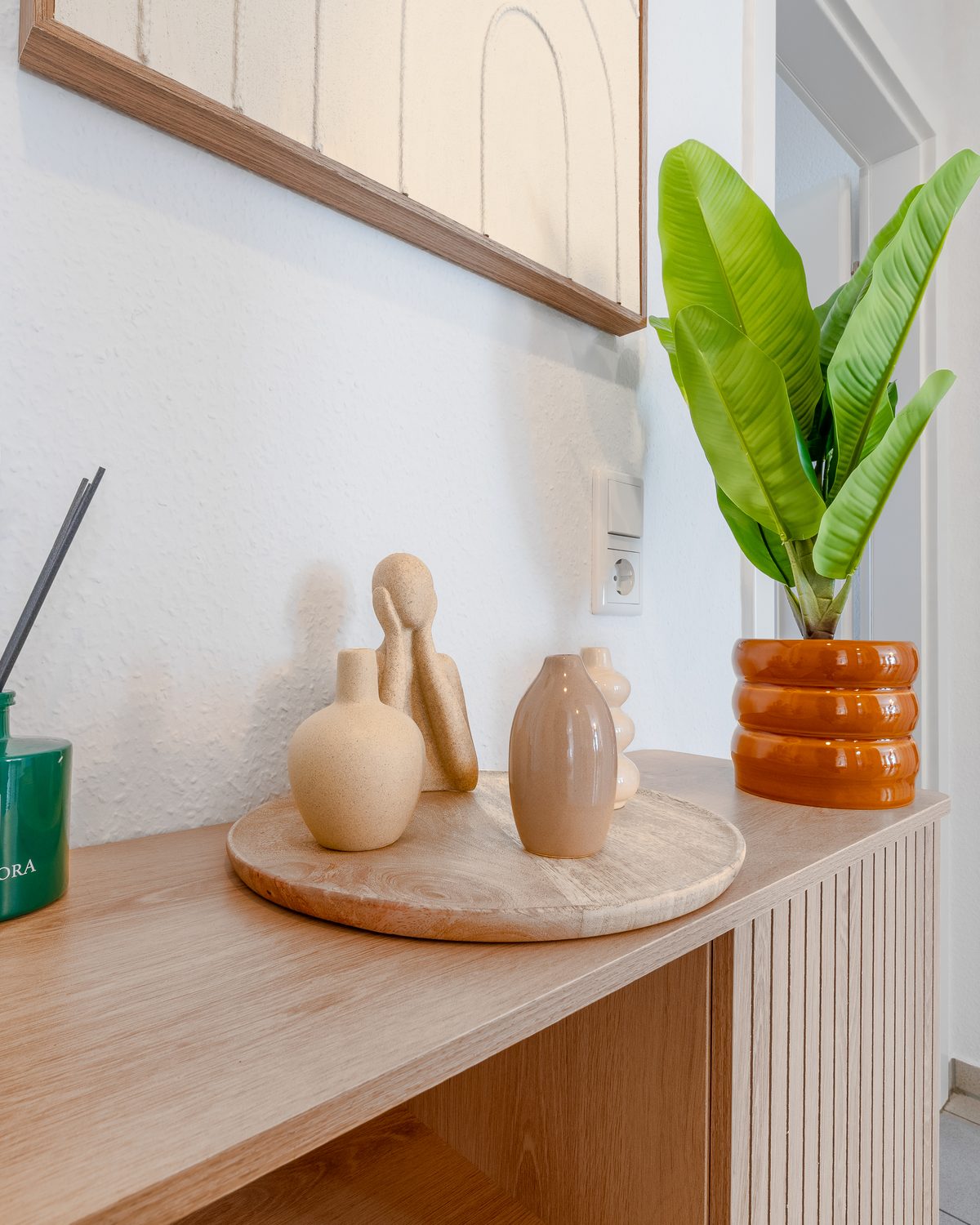 Sideboard mit Duftstäbchen, Dekoobjekten und Zimmerpflanze