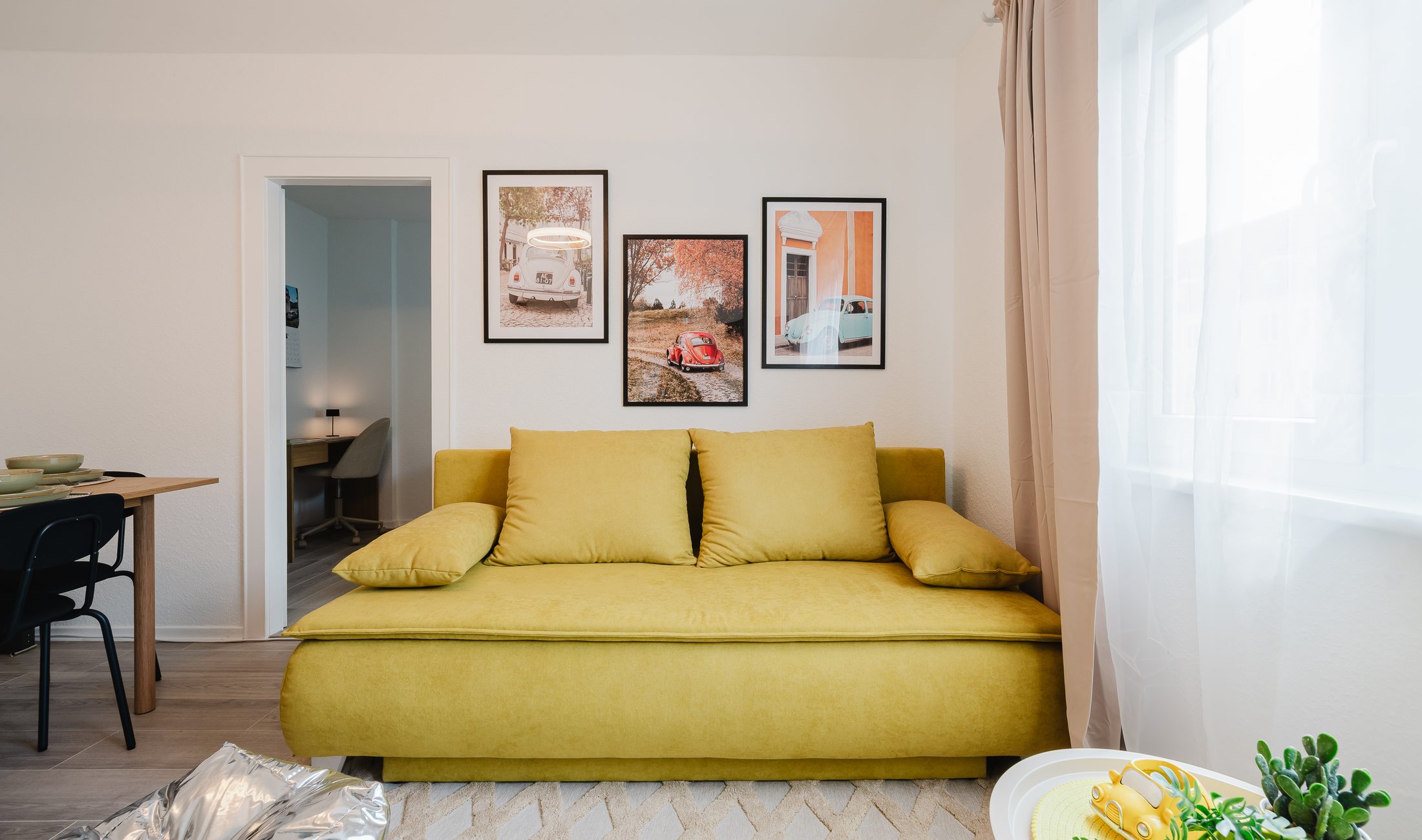 Wohnbereich des Beetle Apartments mit gelbem Sofa und Bilderwand