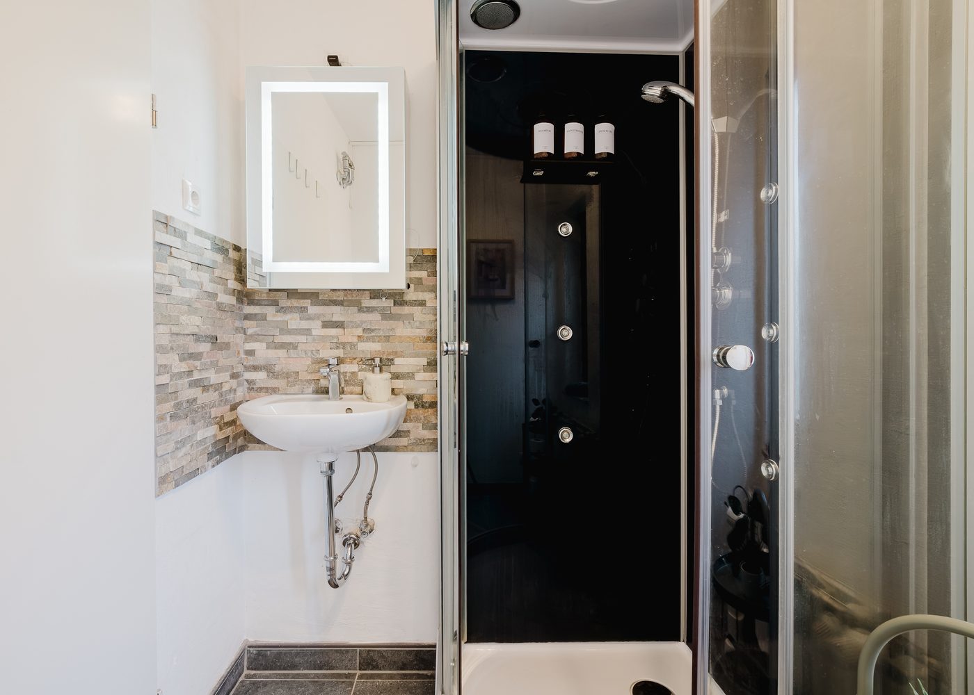 Badezimmer der Kirchenblick-Maisonette mit Duschkabine, Waschbecken und beleuchtetem Spiegel