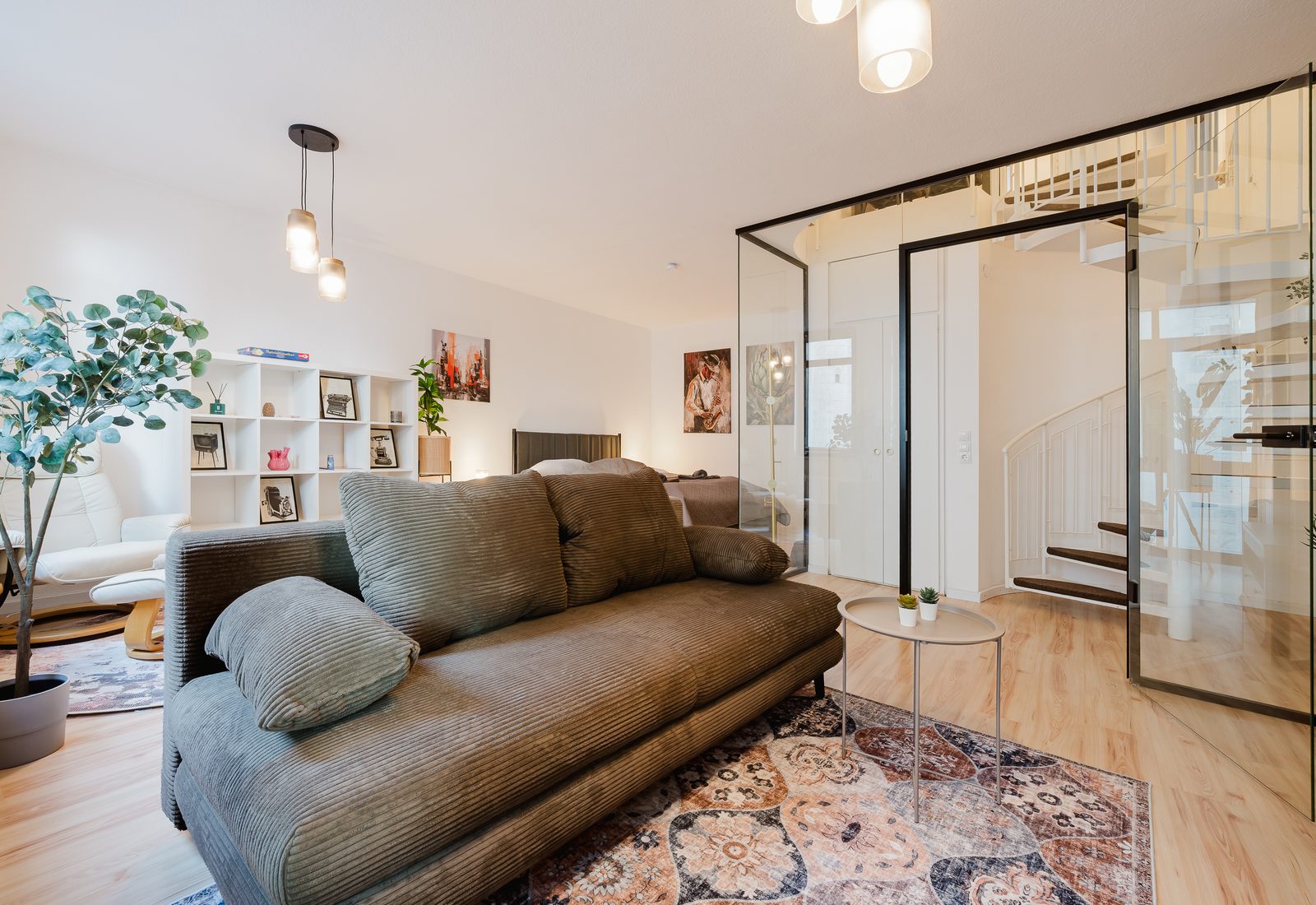 Wohnbereich der Kirchenblick-Maisonette mit großem Sofa und verglastem Treppenaufgang